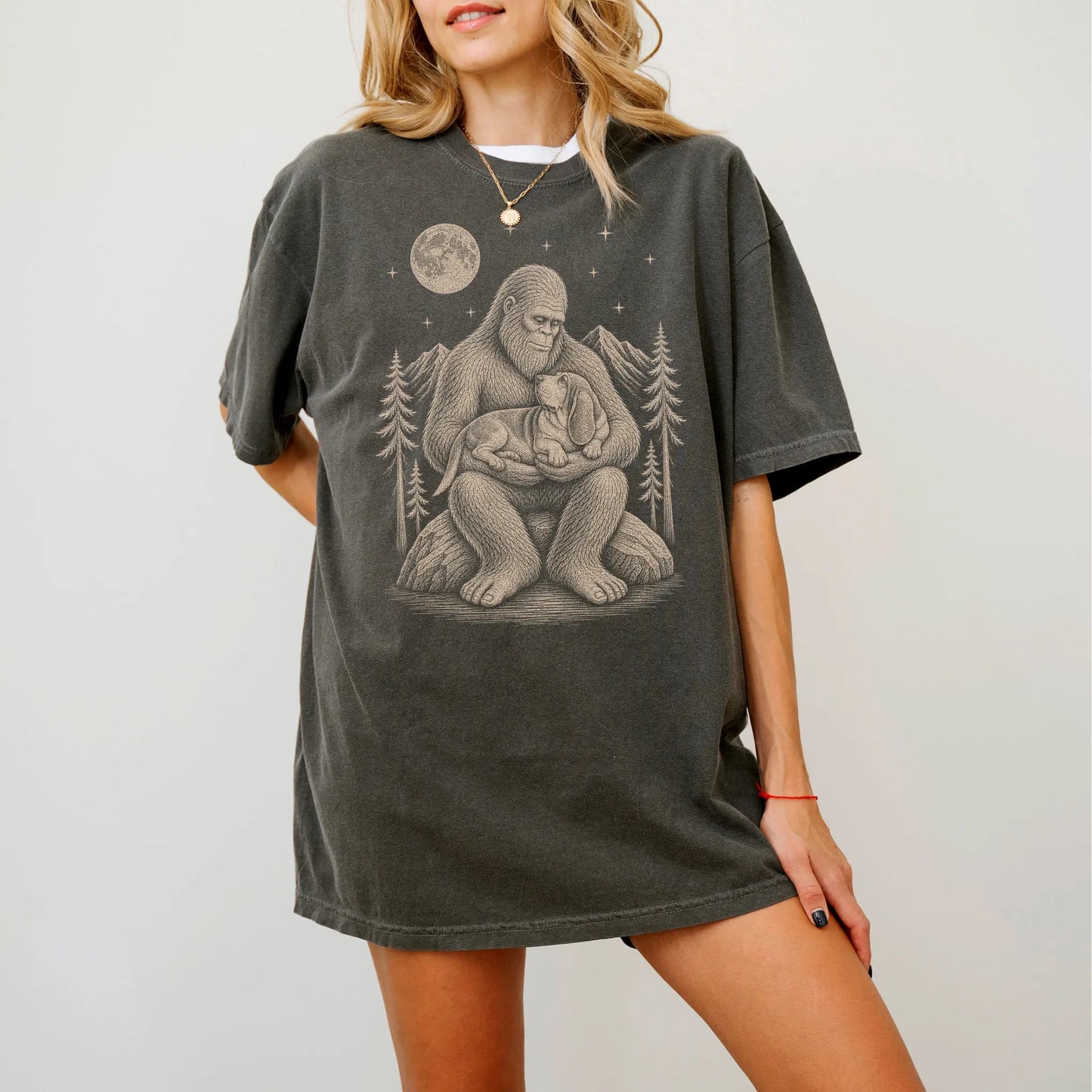 Model wearing a Pepper Comfort Colors® T-shirt showing Bigfoot holding a Basset Hound