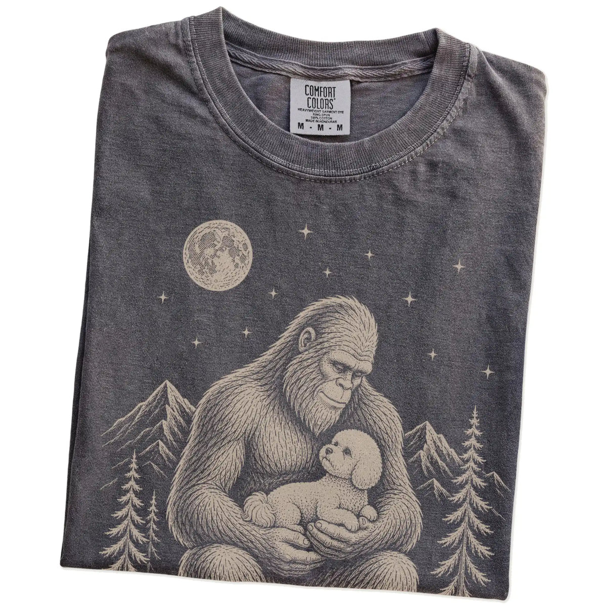 Folded Pepper Comfort Colors® T-shirt showing Bigfoot holding a Bichon Frise