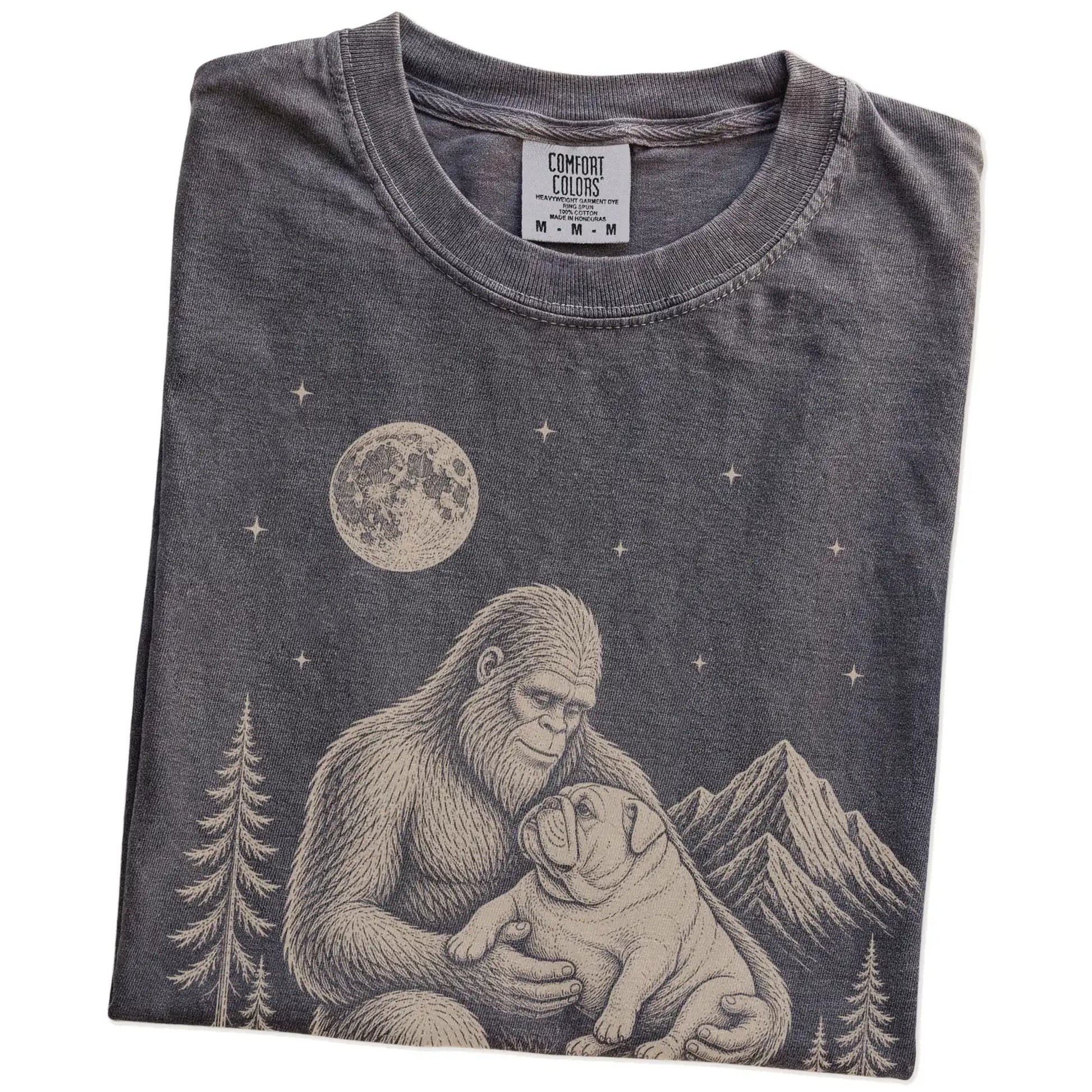 Folded Pepper Comfort Colors® T-shirt showing Bigfoot holding a Bulldog