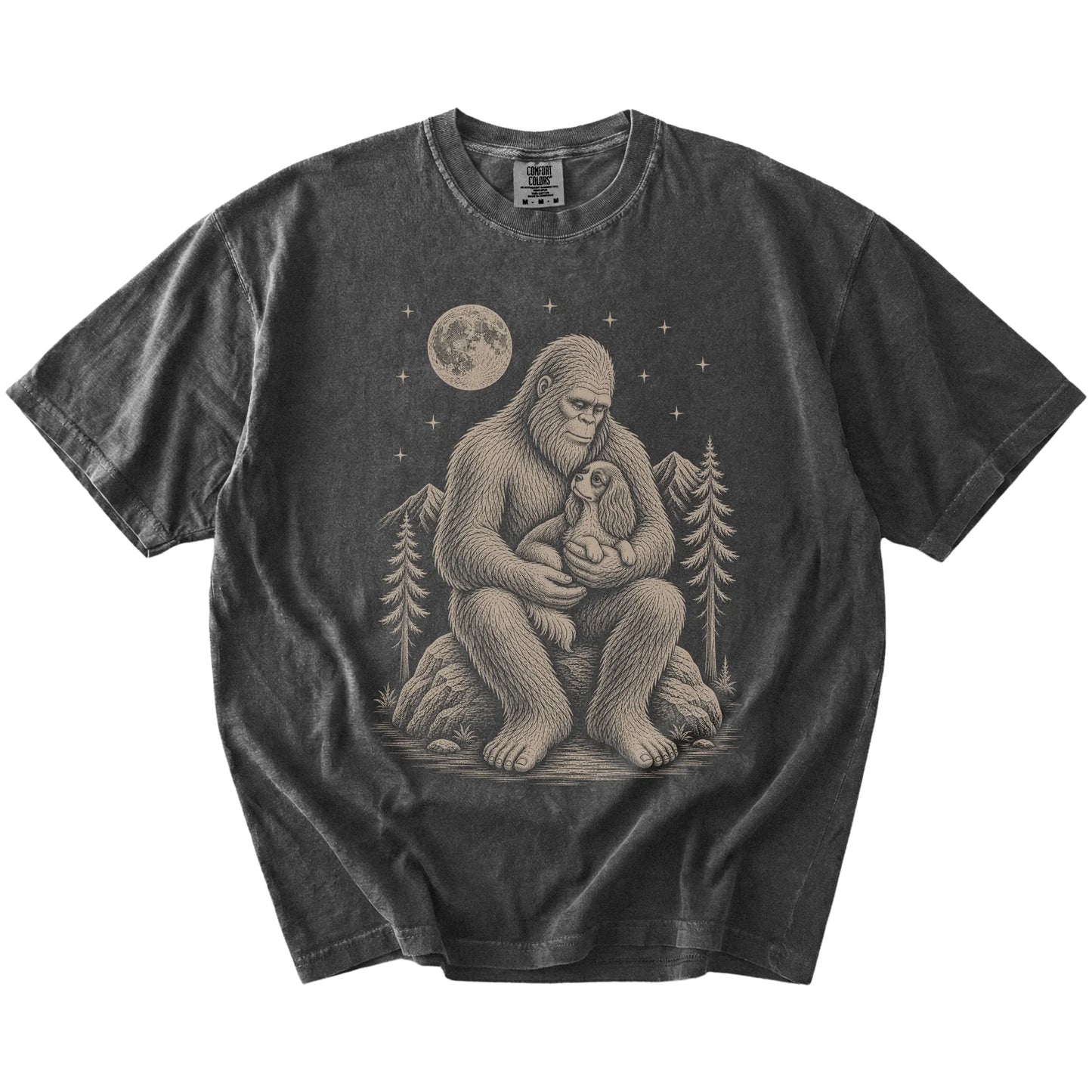 Bigfoot holding a Cavalier King Charles Spaniel on a Pepper Comfort Colors® T-shirt