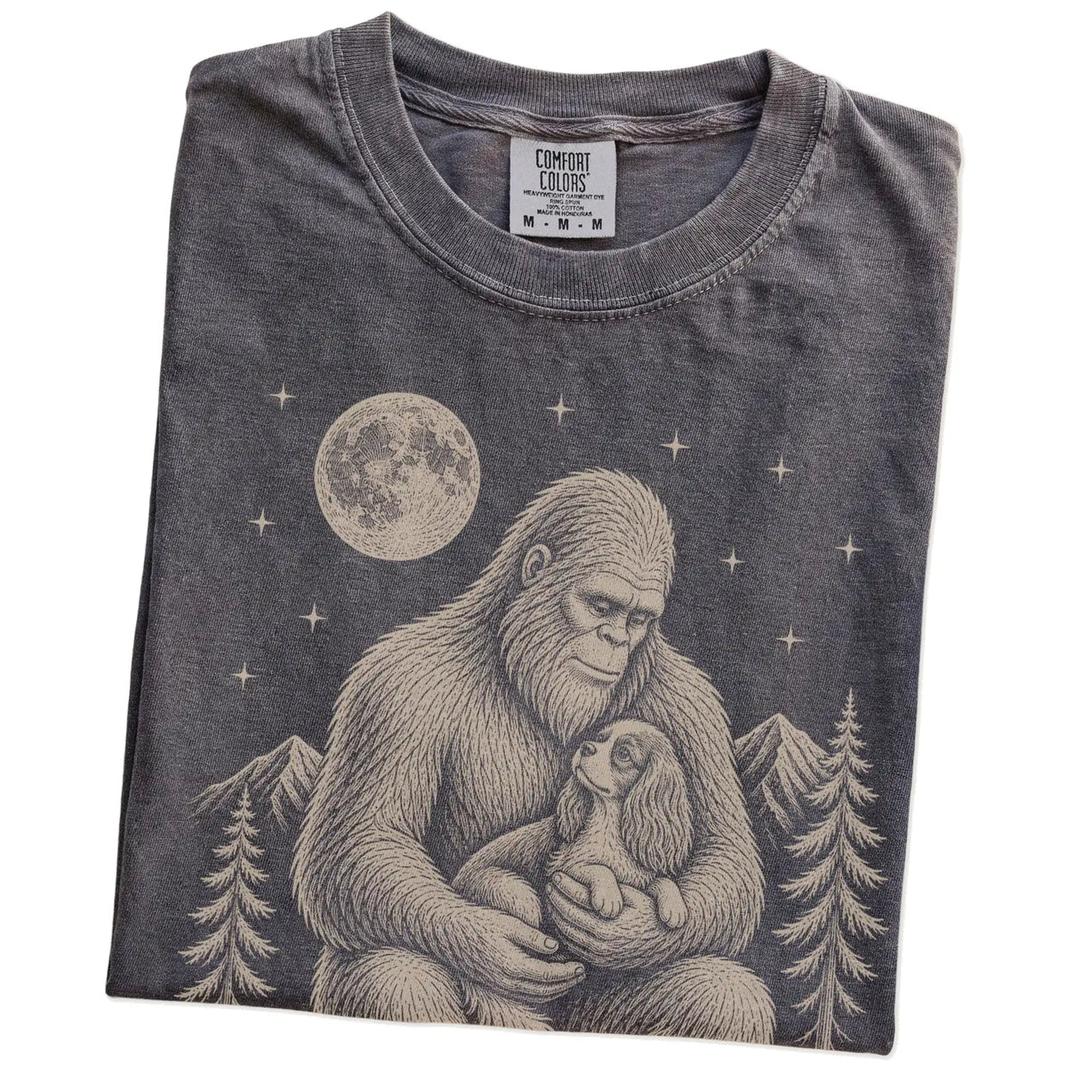 Folded Pepper Comfort Colors® T-shirt showing Bigfoot holding a Cavalier King Charles Spaniel