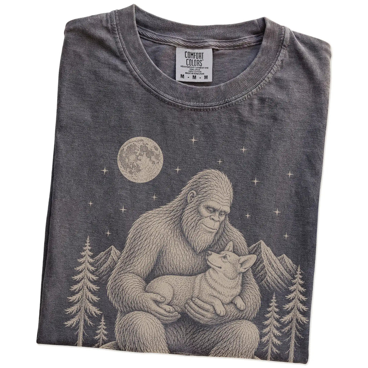 Folded Pepper Comfort Colors® T-shirt showing Bigfoot holding a Corgi
