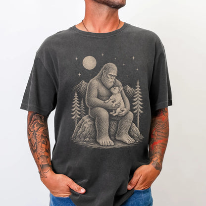 Model wearing a Pepper Comfort Colors® T-shirt showing Bigfoot holding a French Bulldog
