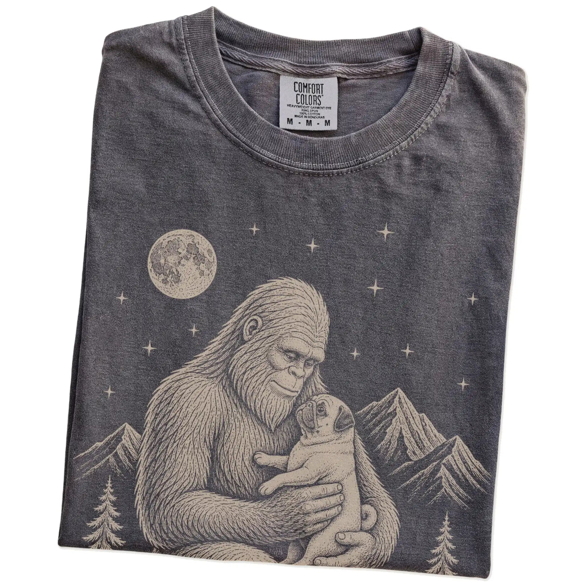 Folded Pepper Comfort Colors® T-shirt showing Bigfoot holding a Pug