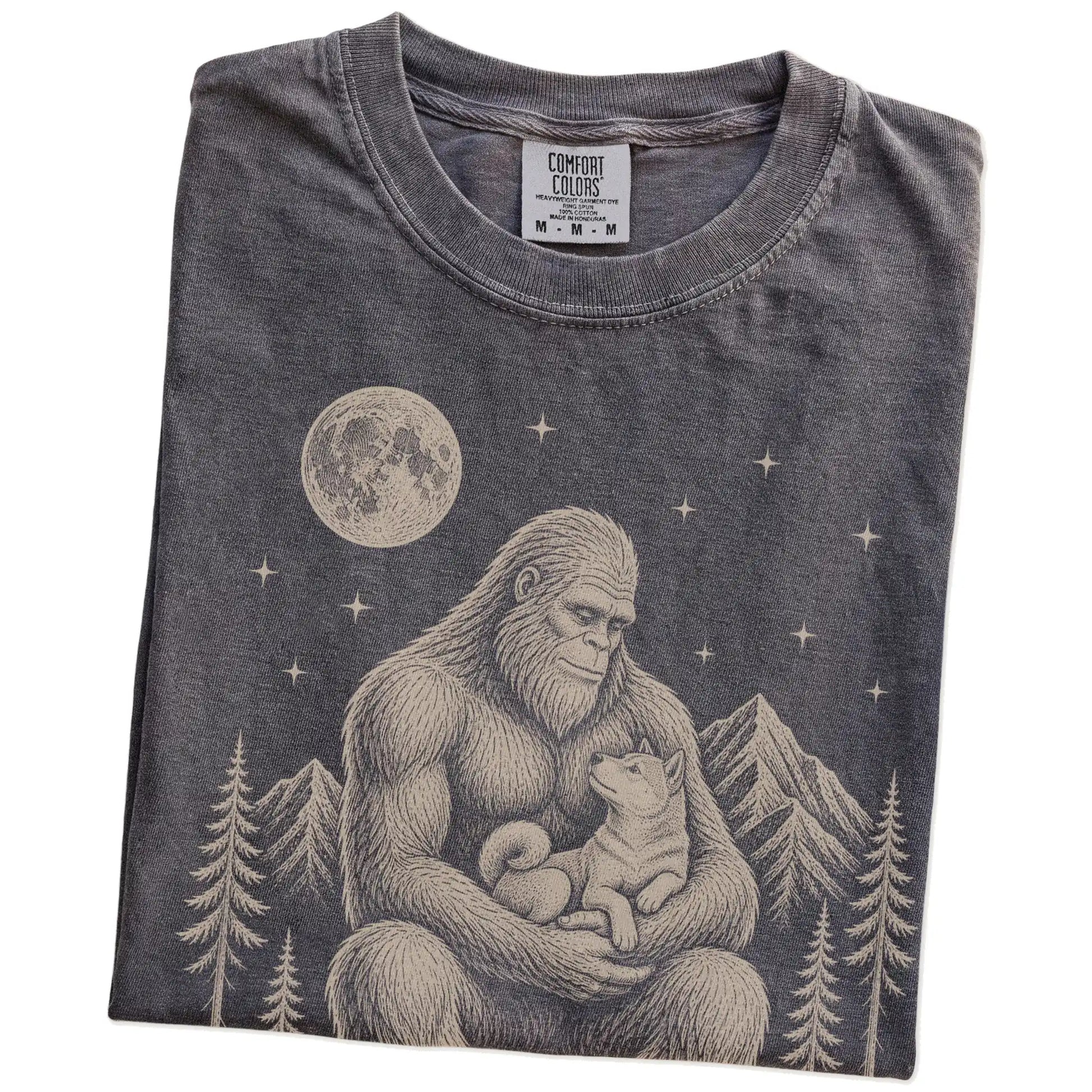 Folded Pepper Comfort Colors® T-shirt showing Bigfoot holding a Shiba Inu