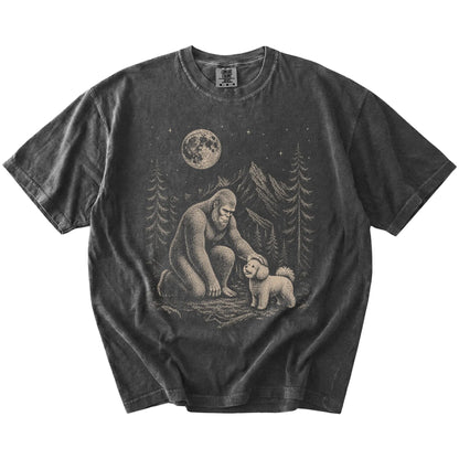 Bigfoot petting a Bichon Frise beneath the moon in a pine forest on a Pepper Comfort Colors® T-shirt