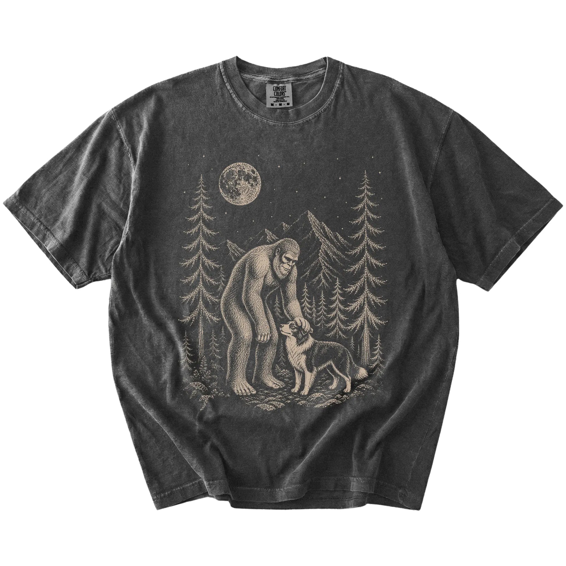 Bigfoot petting a Border Collie beneath the moon in a pine forest on a Pepper Comfort Colors® T-shirt