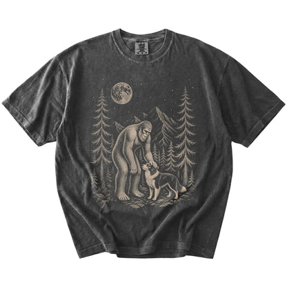 Bigfoot petting a Border Collie beneath the moon in a pine forest on a Pepper Comfort Colors® T-shirt