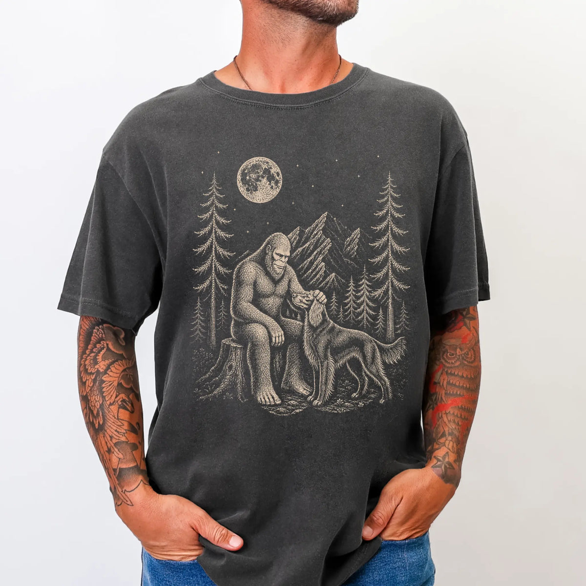 Model wearing a Pepper Comfort Colors® T-shirt with bigfoot petting a irish setter beneath the moon in a pine forest