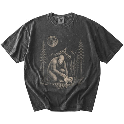 Bigfoot petting a Pomeranian beneath the moon in a pine forest on a Pepper Comfort Colors® T-shirt