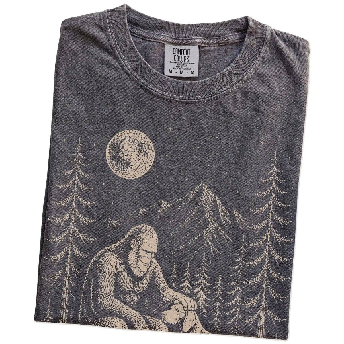Folded Pepper Comfort Colors® T-shirt showing bigfoot petting a weimaraner beneath the moon in a pine forest