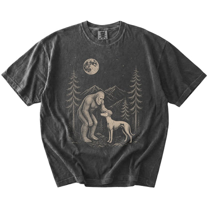 Bigfoot petting a Whippet beneath the moon in a pine forest on a Pepper Comfort Colors® T-shirt
