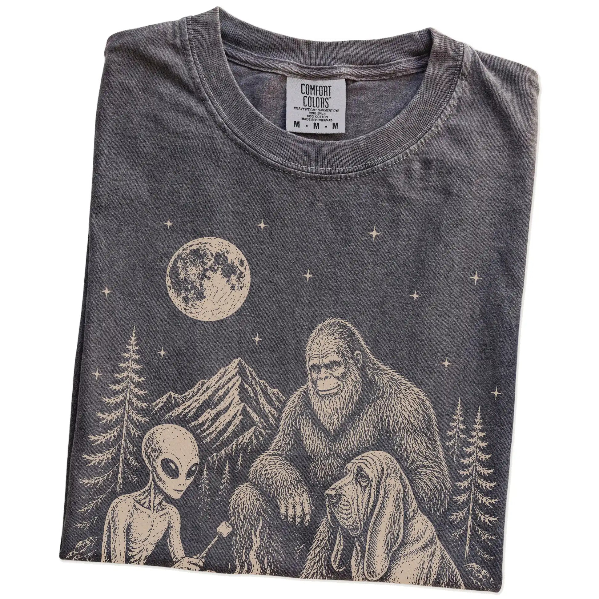 Folded Pepper Comfort Colors® T-shirt showing Bloodhound camping with Bigfoot and an alien