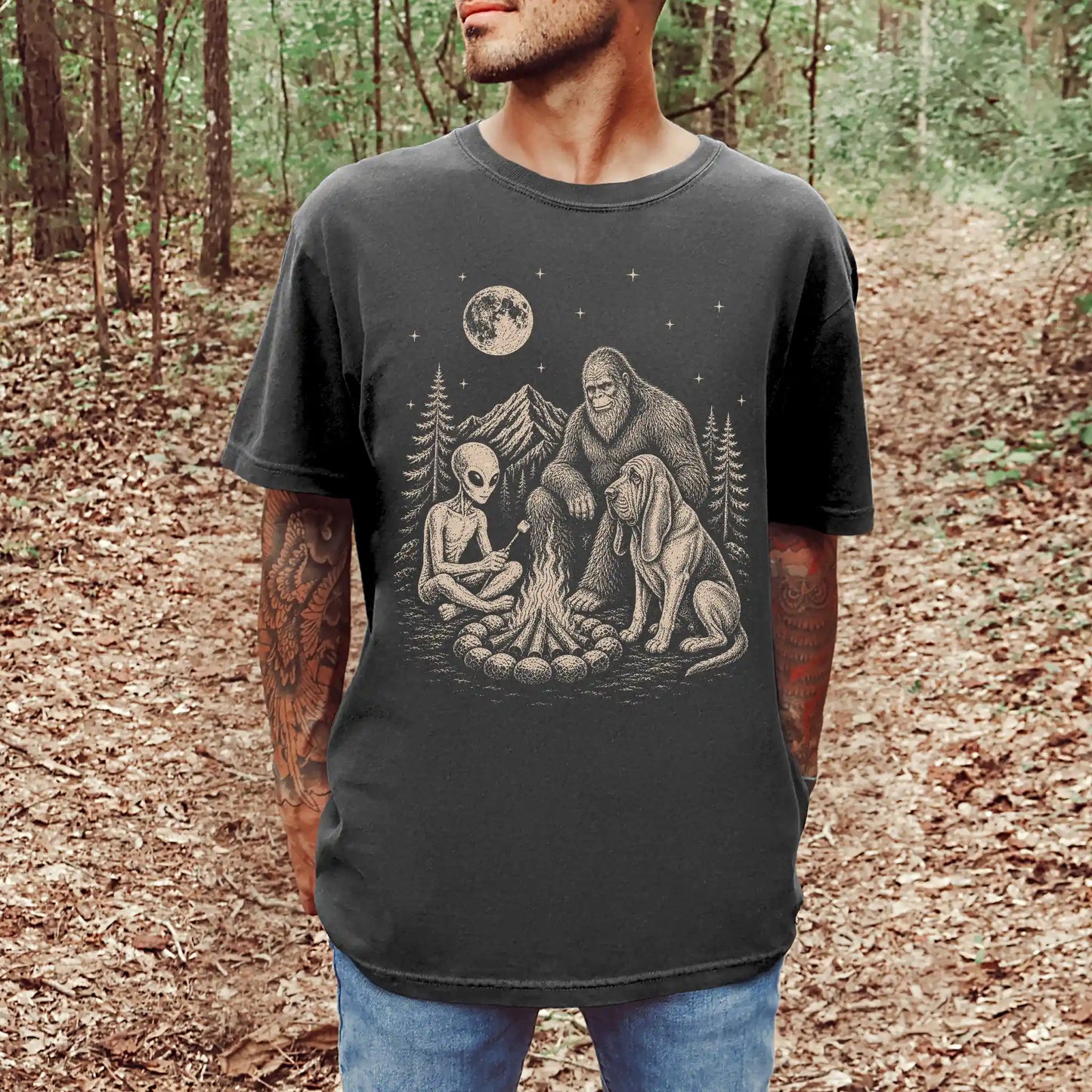 Model wearing a Pepper Comfort Colors® T-shirt showing Bloodhound camping with Bigfoot and an alien