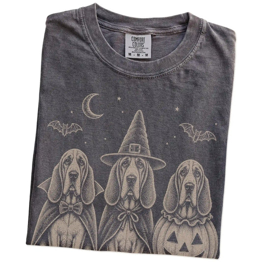 Folded Pepper Comfort Colors® T-shirt showing three Bloodhound dogs dressed for Halloween beneath bats and a crescent moon