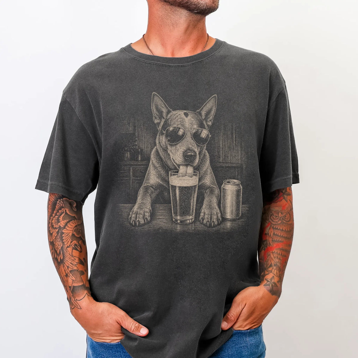 Model wearing a Pepper Comfort Colors® t-shirt with Blue Heeler sneaking a drink from a pint