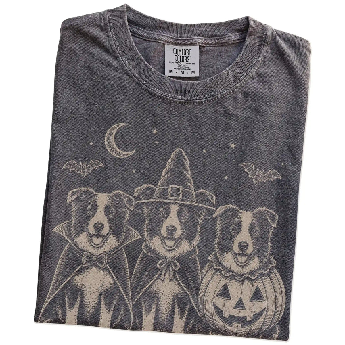 Folded Pepper Comfort Colors® T-shirt showing three Border Collie dogs dressed for Halloween beneath bats and a crescent moon
