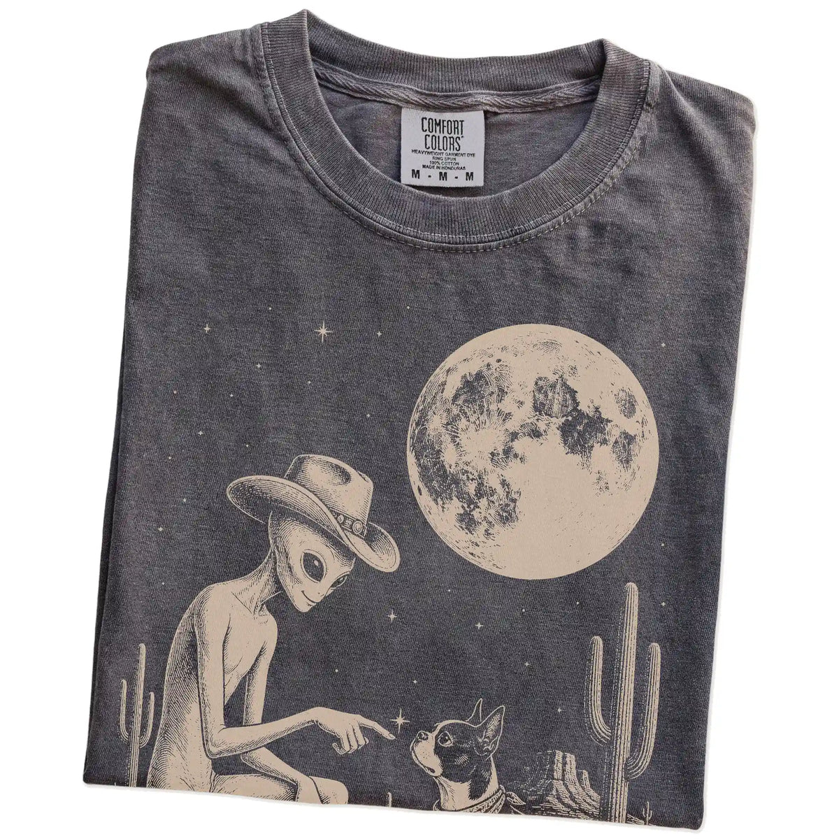 Folded Pepper Comfort Colors® T-shirt showing cowboy alien fist-bumping a boston terrier beneath the moon
