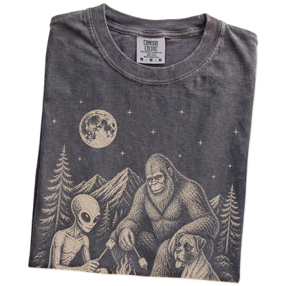 Folded Pepper Comfort Colors® T-shirt showing Boxer camping with Bigfoot and an alien
