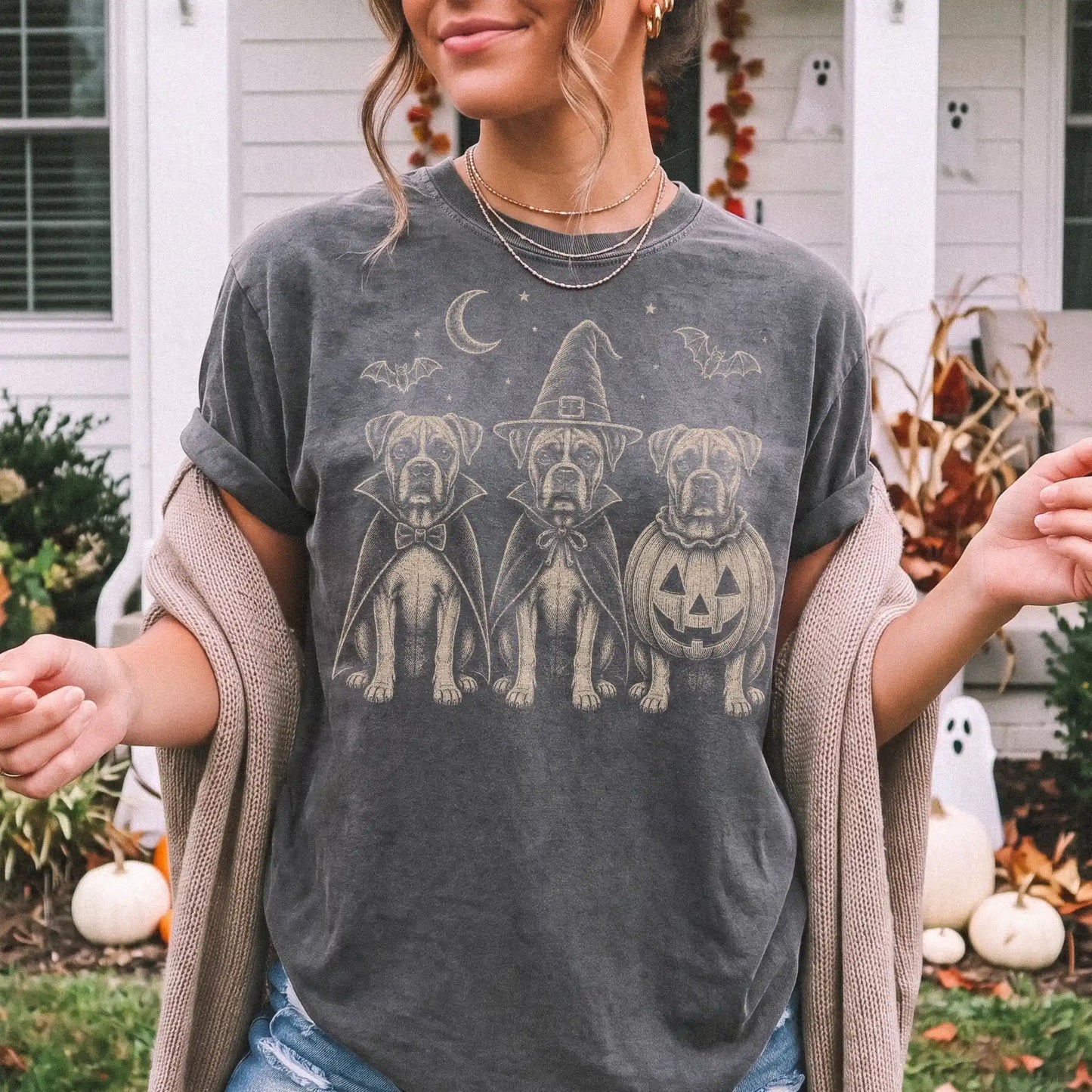 Model wearing a Pepper Comfort Colors® T-shirt showing three Boxer dogs dressed for Halloween beneath bats and a crescent moo