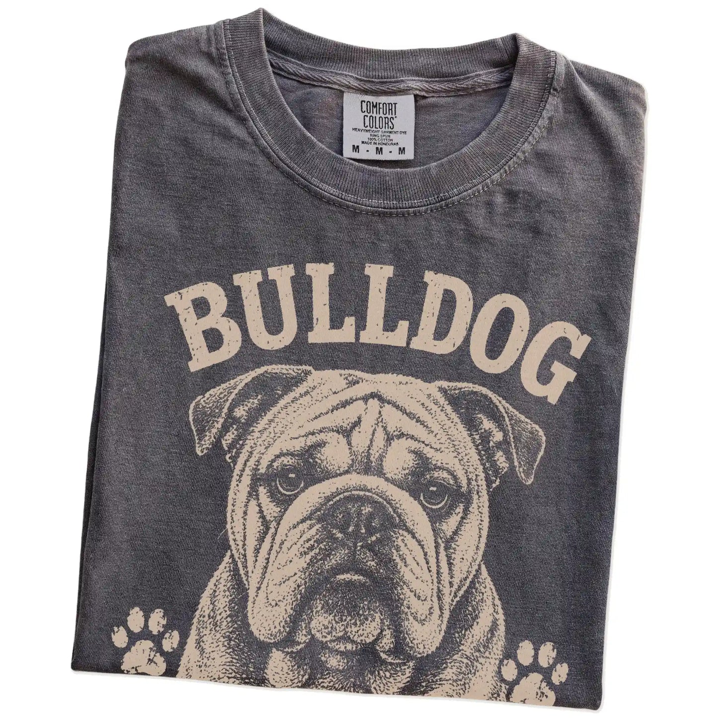 Folded Pepper Comfort Colors® T-shirt showing Bulldog design with “Built Tough, Runs On Snacks” lettering
