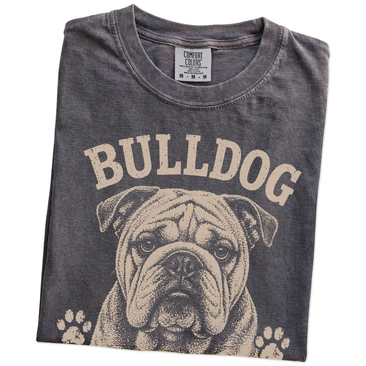 Folded Pepper Comfort Colors® T-shirt showing Bulldog design with “Built Tough, Runs On Snacks” lettering