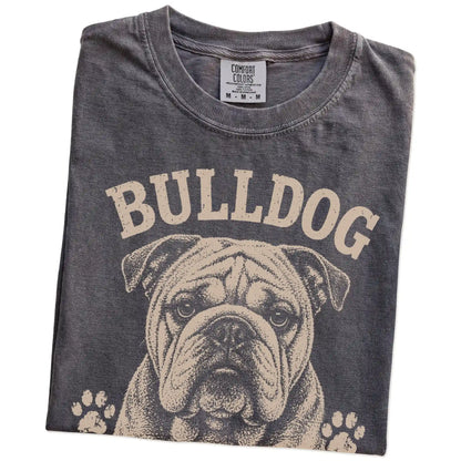 Folded Pepper Comfort Colors® T-shirt showing Bulldog design with “Built Tough, Runs On Snacks” lettering
