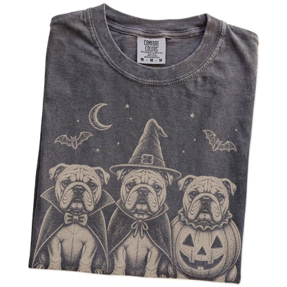 Folded Pepper Comfort Colors® T-shirt showing three Bulldog dogs dressed for Halloween beneath bats and a crescent moon