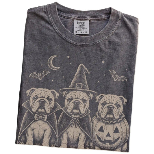 Folded Pepper Comfort Colors® T-shirt showing three Bulldog dogs dressed for Halloween beneath bats and a crescent moon