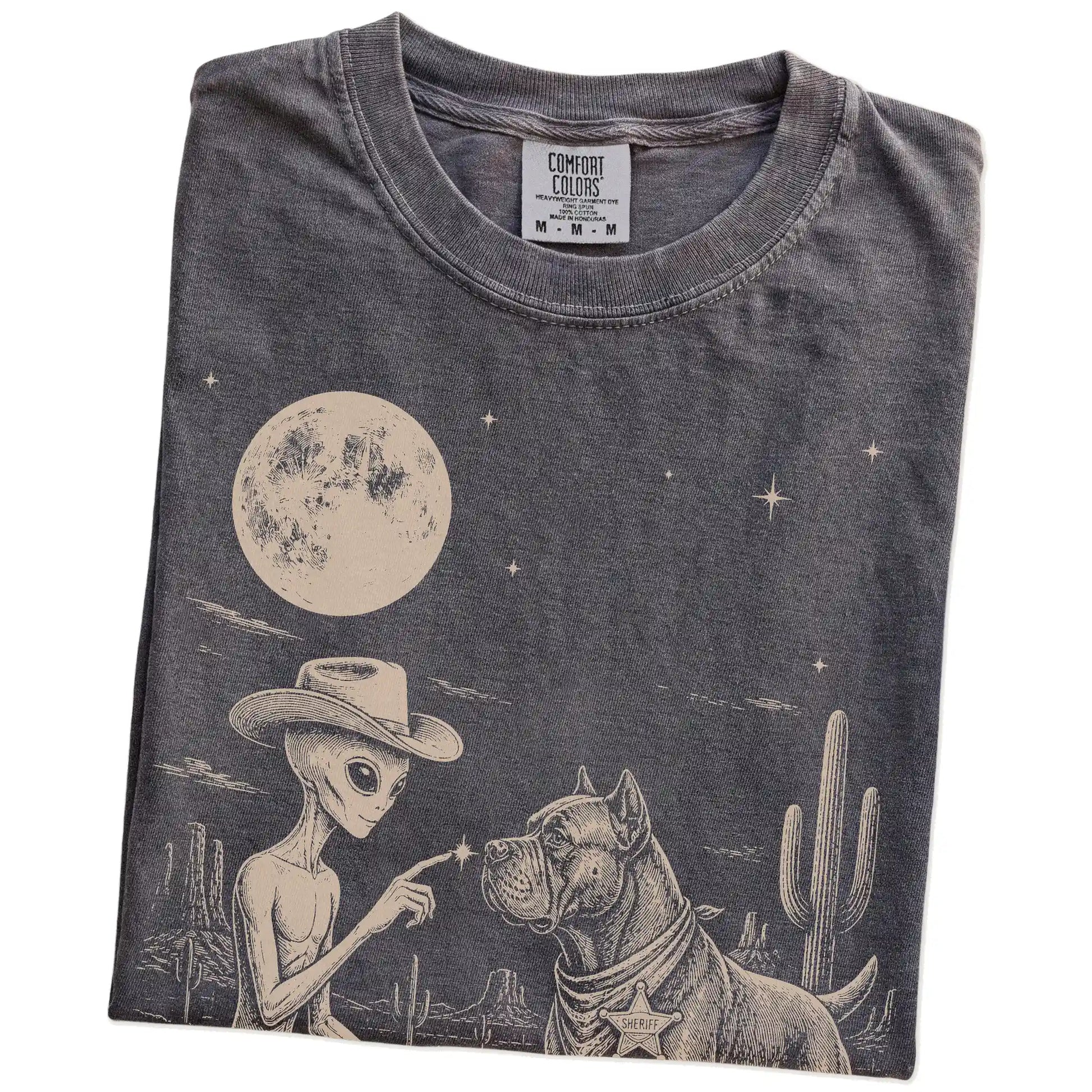 Folded Pepper Comfort Colors® T-shirt showing cowboy alien fist-bumping a cane corso beneath the moon