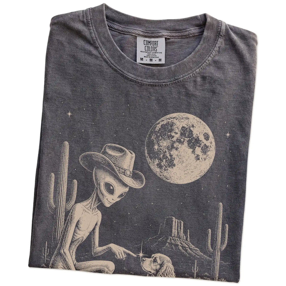 Folded Pepper Comfort Colors® T-shirt showing cowboy alien fist-bumping a cocker spaniel beneath the moon