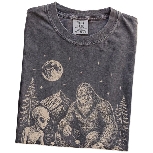 Folded Pepper Comfort Colors® T-shirt showing Cocker Spaniel camping with Bigfoot and an alien