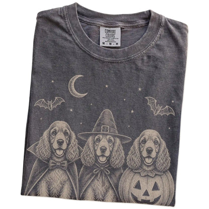 Folded Pepper Comfort Colors® T-shirt showing three Cocker Spaniel dogs dressed for Halloween beneath bats and a crescent moo