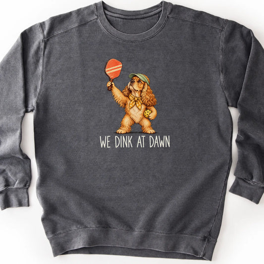 Cocker Spaniel with a pickleball paddle and ball on a Pepper Comfort Colors® sweatshirt with We Dink at Dawn text