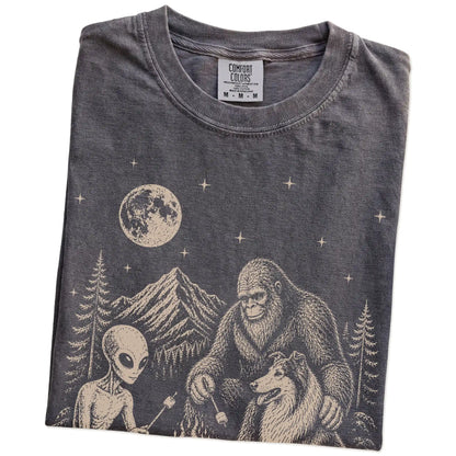 Folded Pepper Comfort Colors® T-shirt showing Collie camping with Bigfoot and an alien