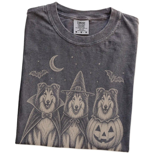 Folded Pepper Comfort Colors® T-shirt showing three Collie dogs dressed for Halloween beneath bats and a crescent moon