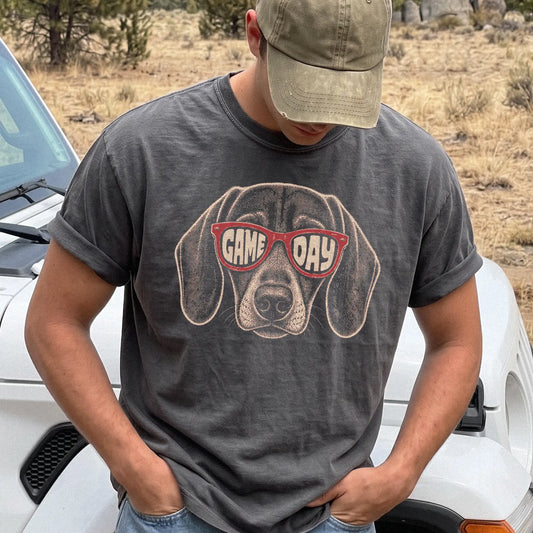 Model wearing a Pepper Comfort Colors® T-shirt with dachshund wearing red game day sunglasses