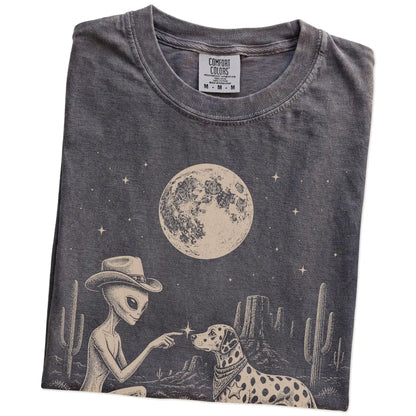 Folded Pepper Comfort Colors® T-shirt showing cowboy alien fist-bumping a dalmatian beneath the moon