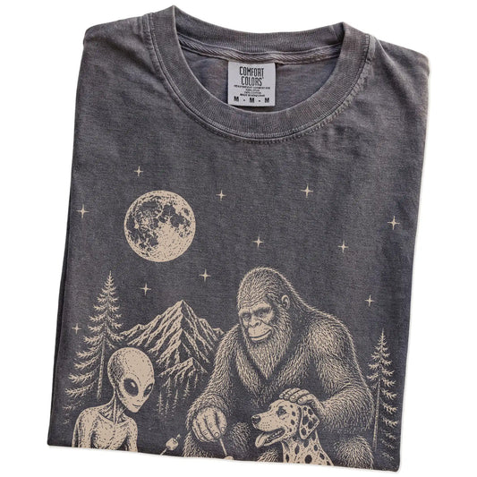 Folded Pepper Comfort Colors® T-shirt showing Dalmatian camping with Bigfoot and an alien
