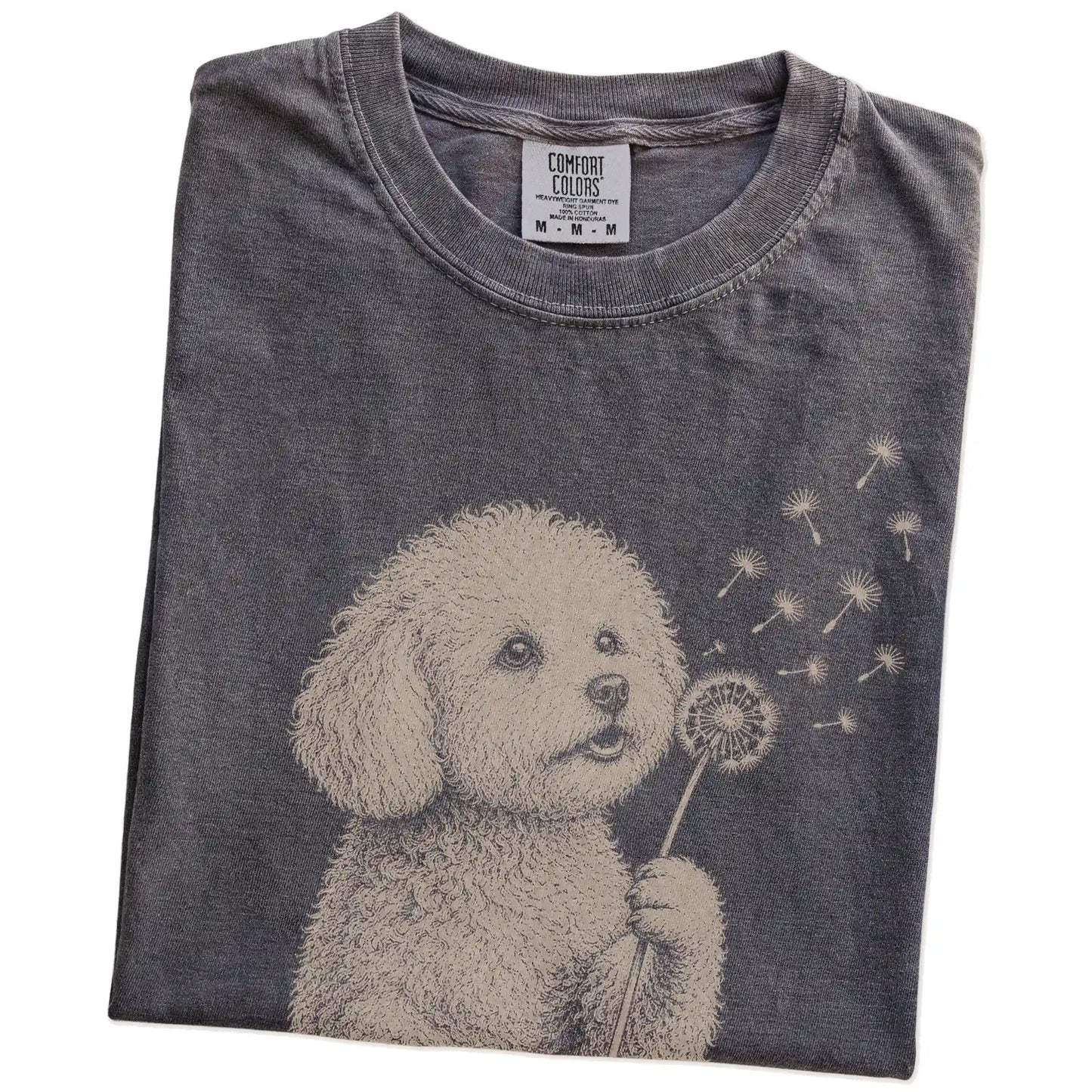 Folded Pepper Comfort Colors® T-shirt showing Bichon Frise portrait with drifting dandelion seeds