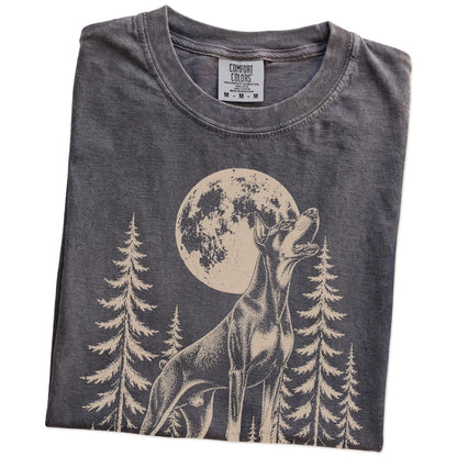 Folded Pepper Comfort Colors® T-shirt showing a Doberman howling beneath the moon and pine trees