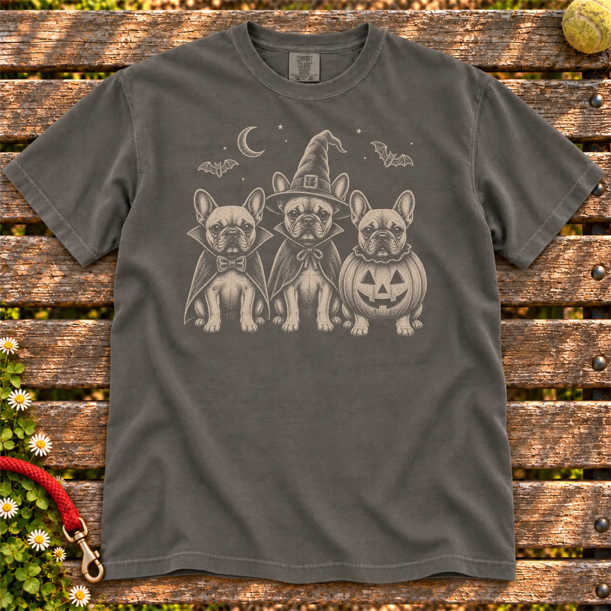 Three French Bulldog dogs dressed for Halloween beneath bats and a crescent moon on a Pepper Comfort Colors® T-shirt