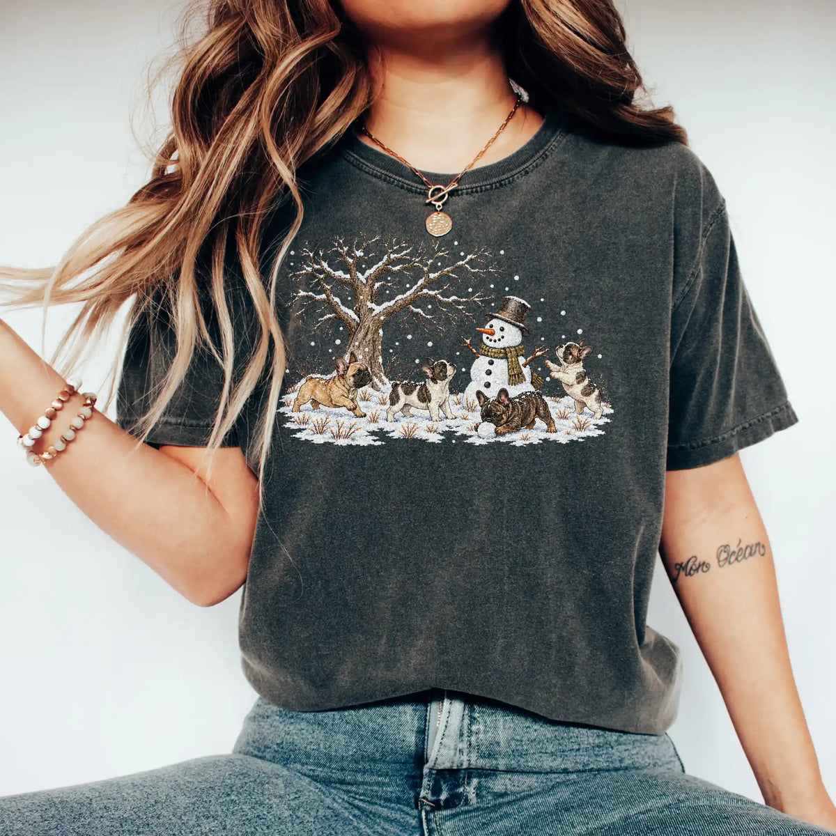 French Bulldog puppies playing in snow with a snowman on a Pepper T-shirt worn by a model