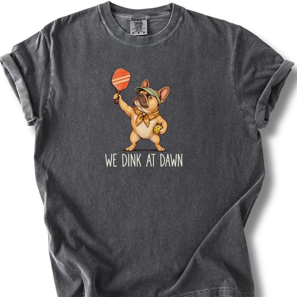 French Bulldog with a pickleball paddle and ball on a Pepper Comfort Colors® T-shirt with We Dink at Dawn text