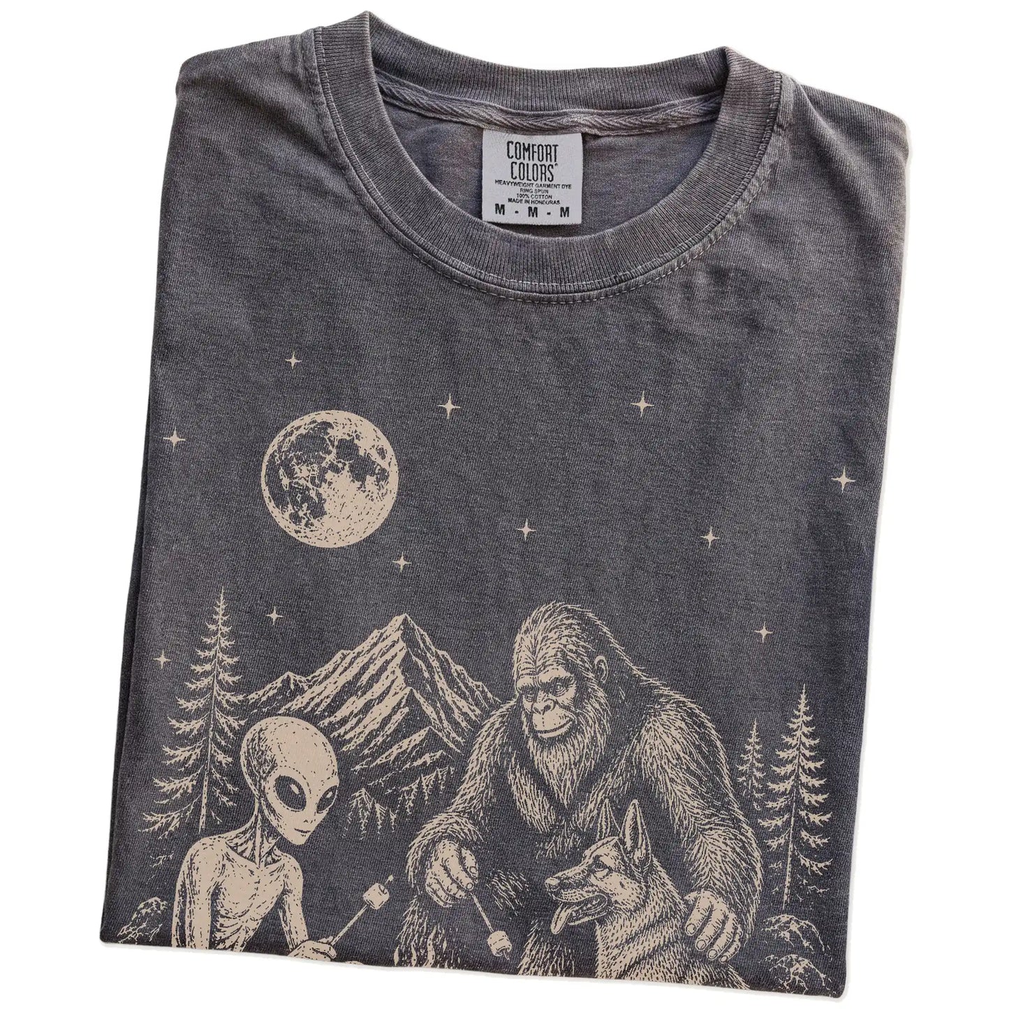 Folded Pepper Comfort Colors® T-shirt showing German Shepherd camping with Bigfoot and an alien