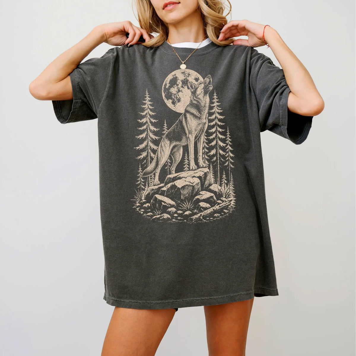 Model wearing a Pepper Comfort Colors® T-shirt with a German Shepherd howling beneath the moon and pine trees