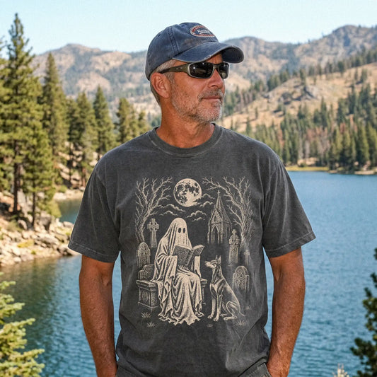 Model wearing a Pepper Comfort Colors® T-shirt showing Doberman beside a reading ghost in a moonlit graveyard