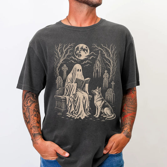 Model wearing a Pepper Comfort Colors® T-shirt showing German Shepherd beside a reading ghost in a moonlit graveyard