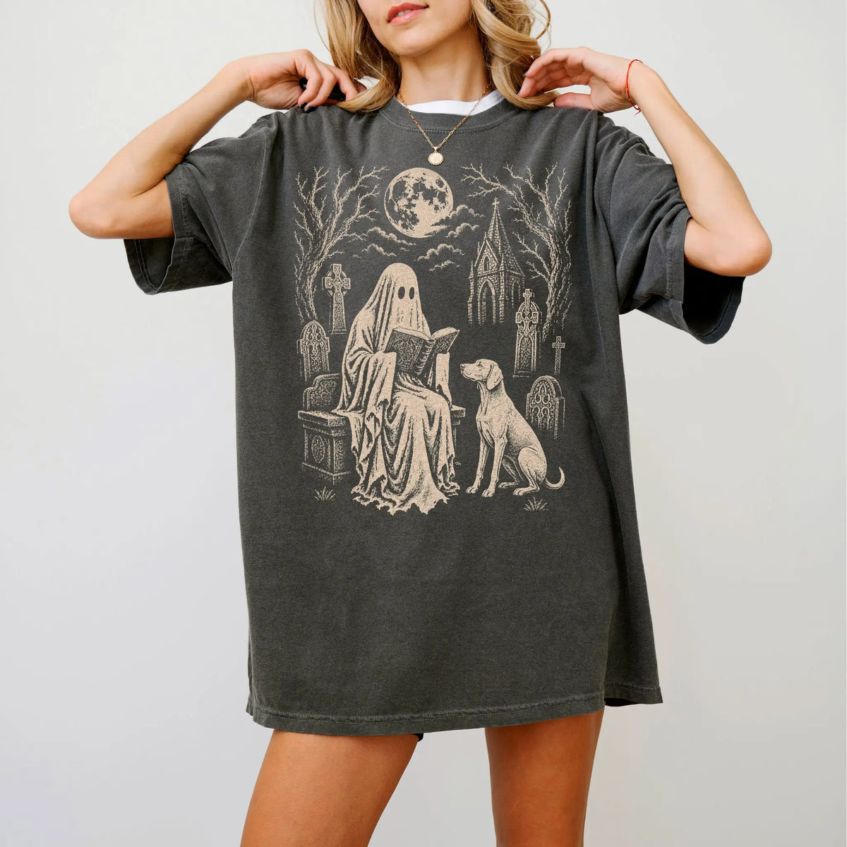 Model wearing a Pepper Comfort Colors® T-shirt showing Weimaraner beside a reading ghost in a moonlit graveyard