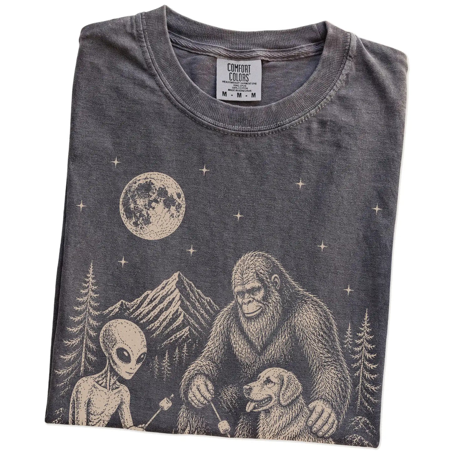 Folded Pepper Comfort Colors® T-shirt showing Golden Retriever camping with Bigfoot and an alien